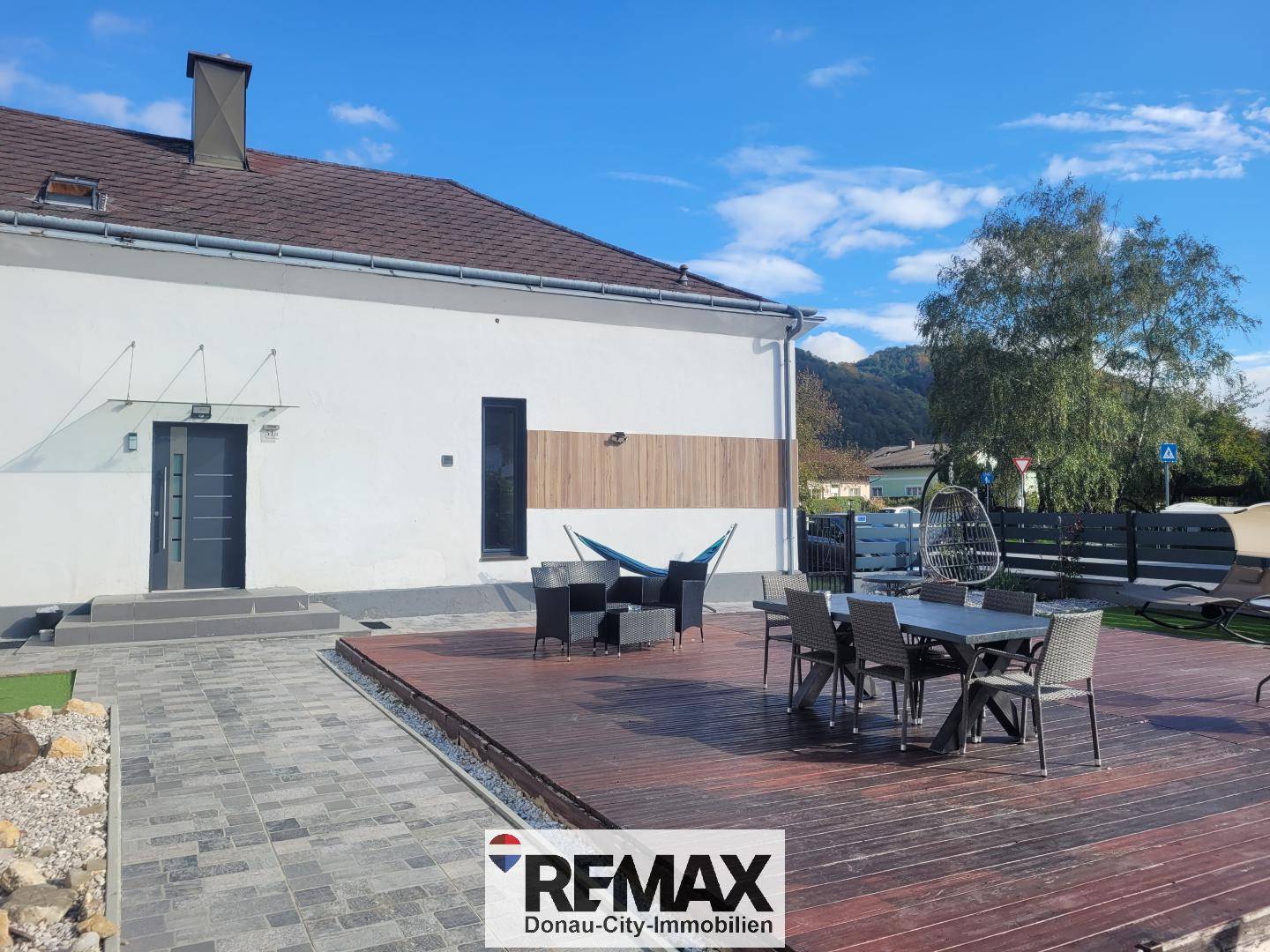 Große Holzterrasse mit modernen Gartenmöbeln und Blick auf die umliegende Natur.