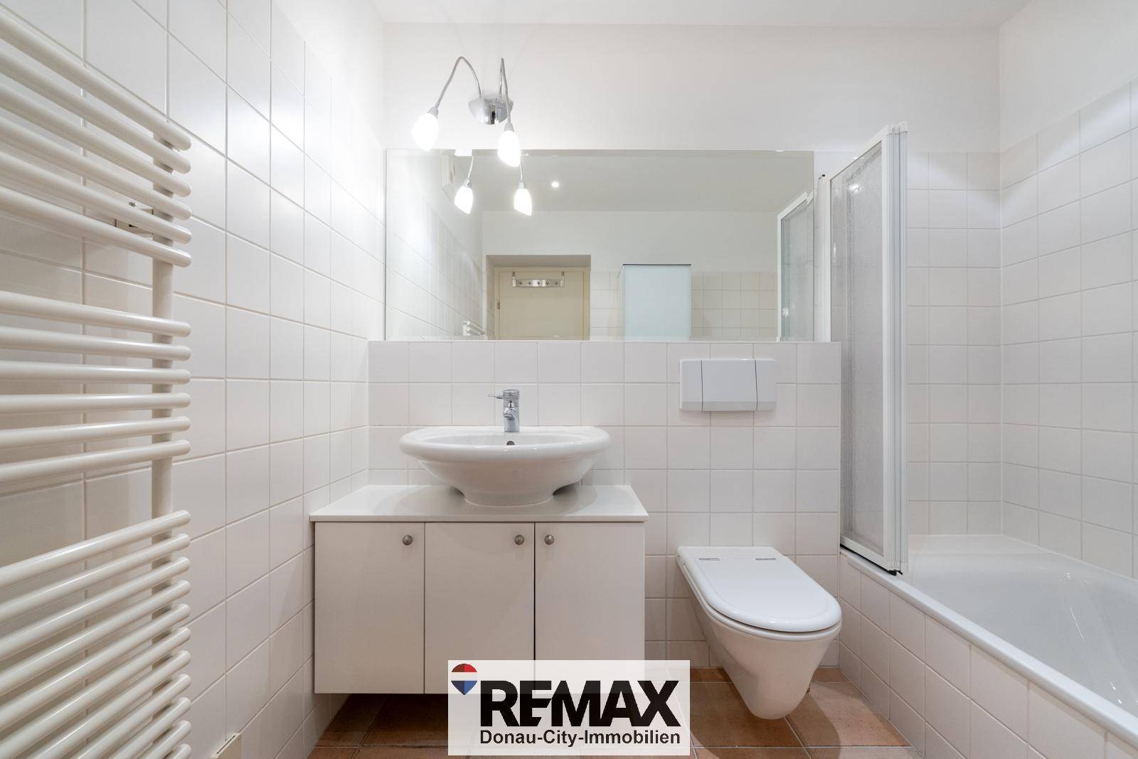 Helles Badezimmer mit Badewanne, WC, Einzelwaschbecken und Handtuchheizkörper.