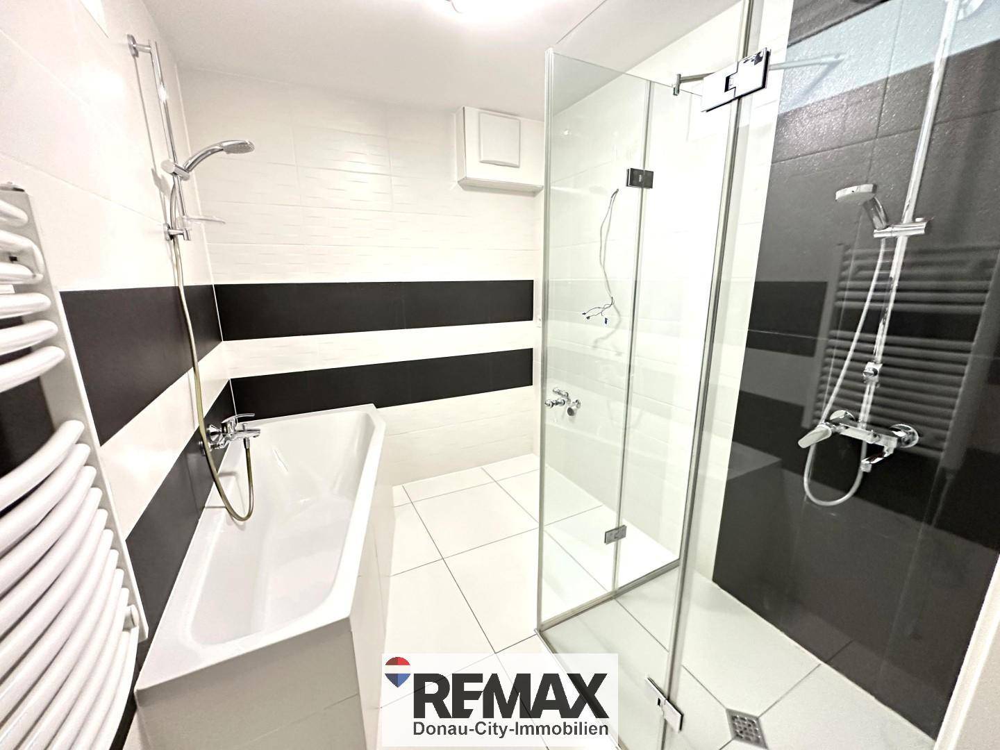 Modernes Badezimmer mit Badewanne, begehbarer Dusche und schwarz-weißen Fliesen.