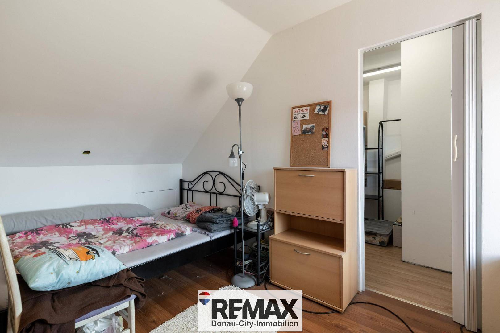 Gemütliches Schlafzimmer im Dachgeschoss mit Einzelbett und schräger Decke.