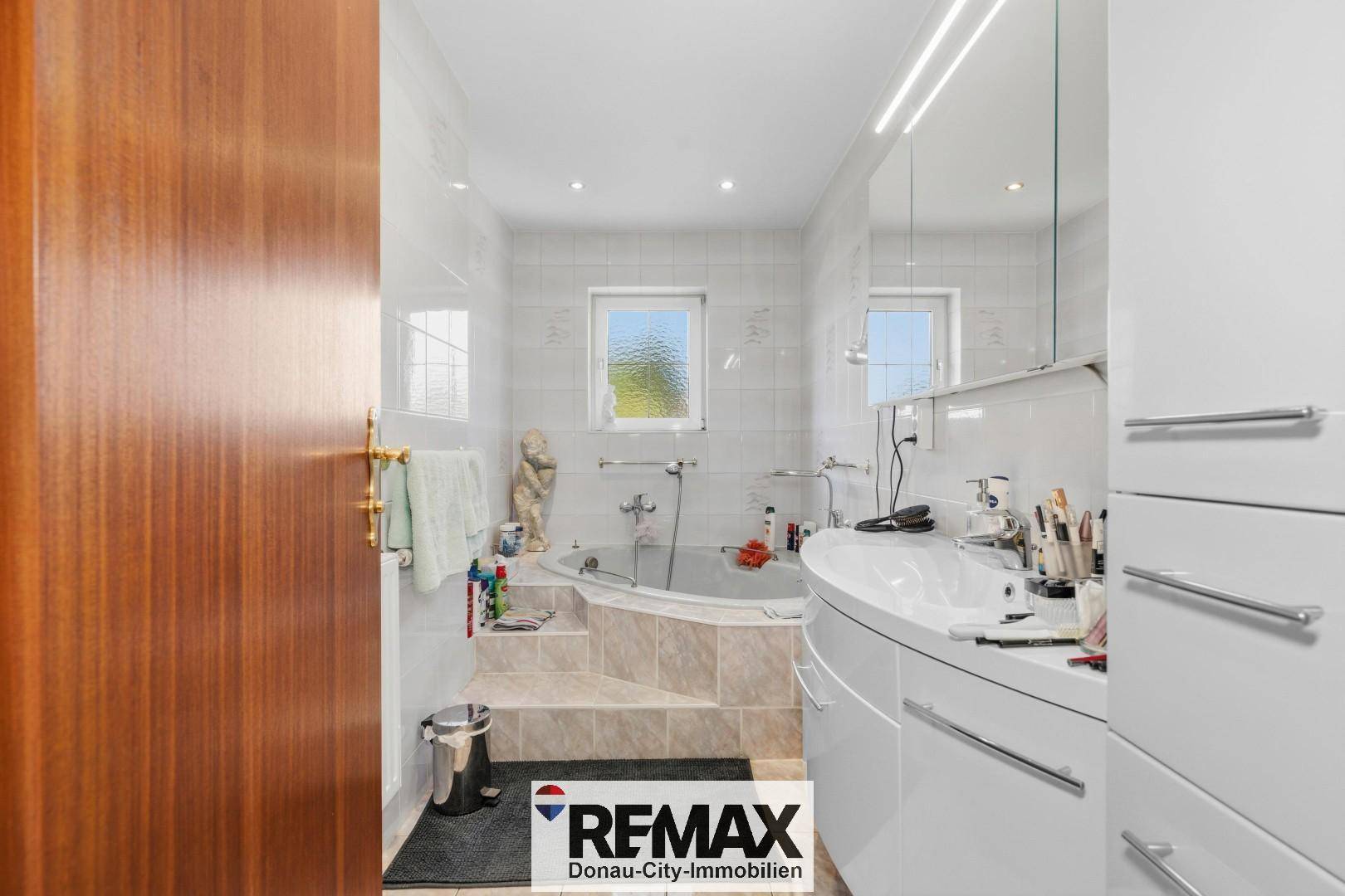 Geräumiges Badezimmer mit Eckbadewanne, Doppelwaschbecken und Fenster.