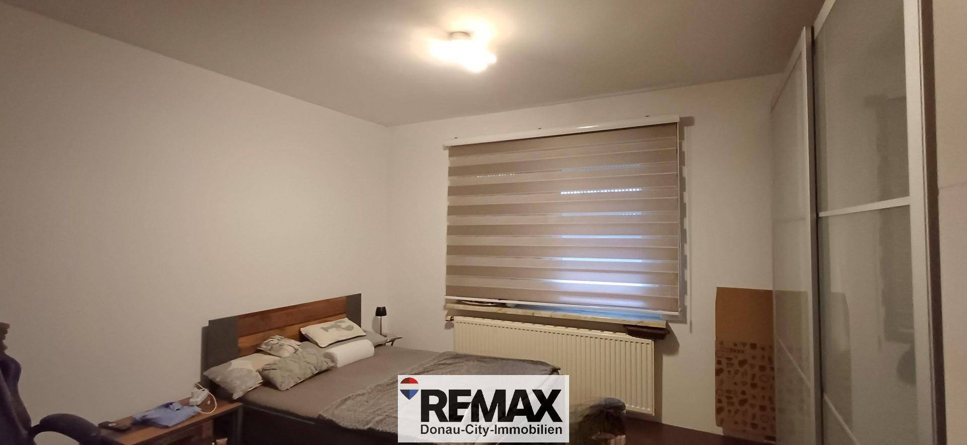 Helles Schlafzimmer mit Bett, Fenster und Heizkörper, bereit zur individuellen Gestaltung.