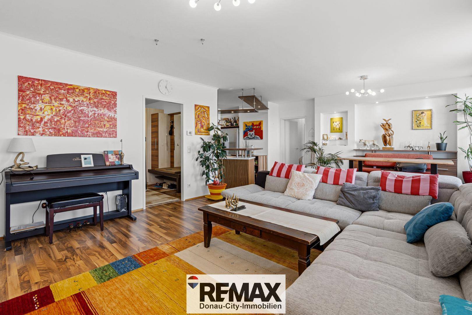 Geräumiger Wohn- und Essbereich mit Holzboden, großem Sofa und Klavier.