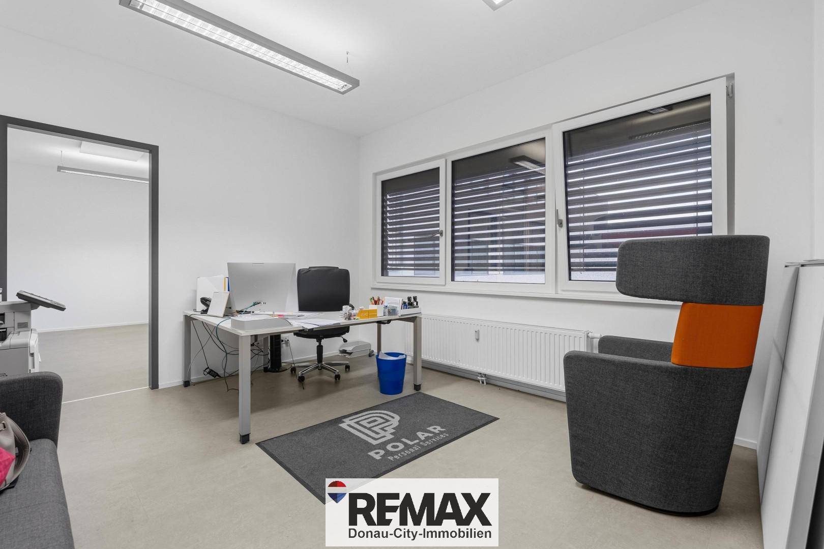 Möbliertes Büro mit Schreibtisch, Bürostuhl und bequemen Sitzgelegenheiten.