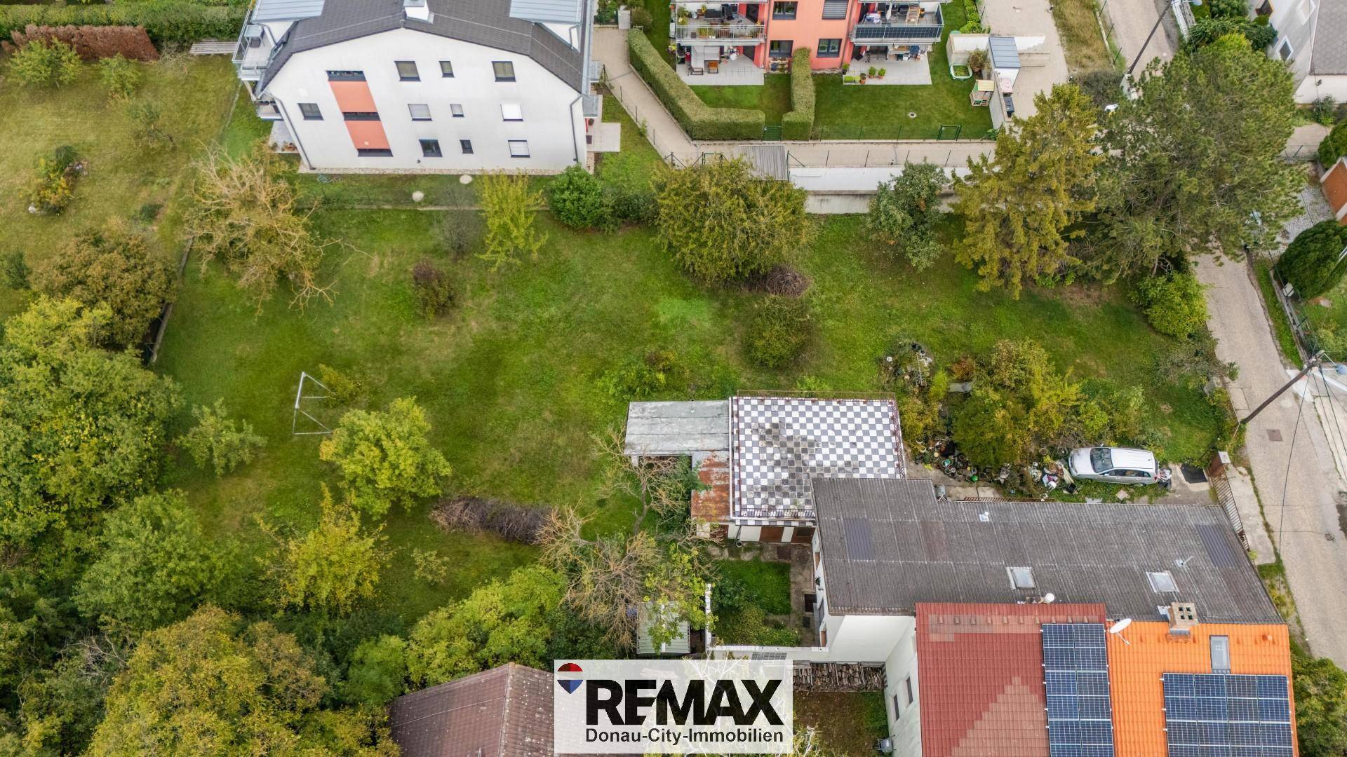 Vogelperspektive des Anwesens mit großem Gartenbereich, umgeben von Bäumen und weiteren Gebäuden.