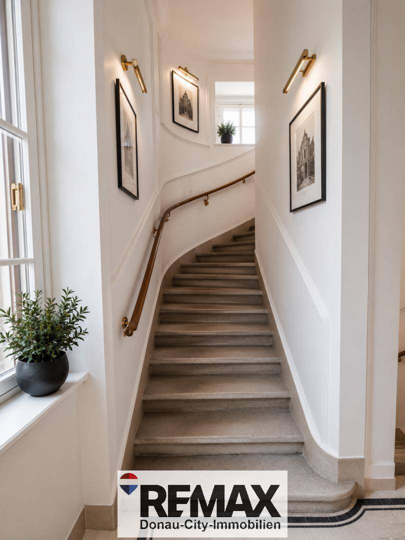 Elegantes Treppenhaus mit geschwungener Holztreppe, hellen Wänden und viel natürlichem Lichteinfall.
