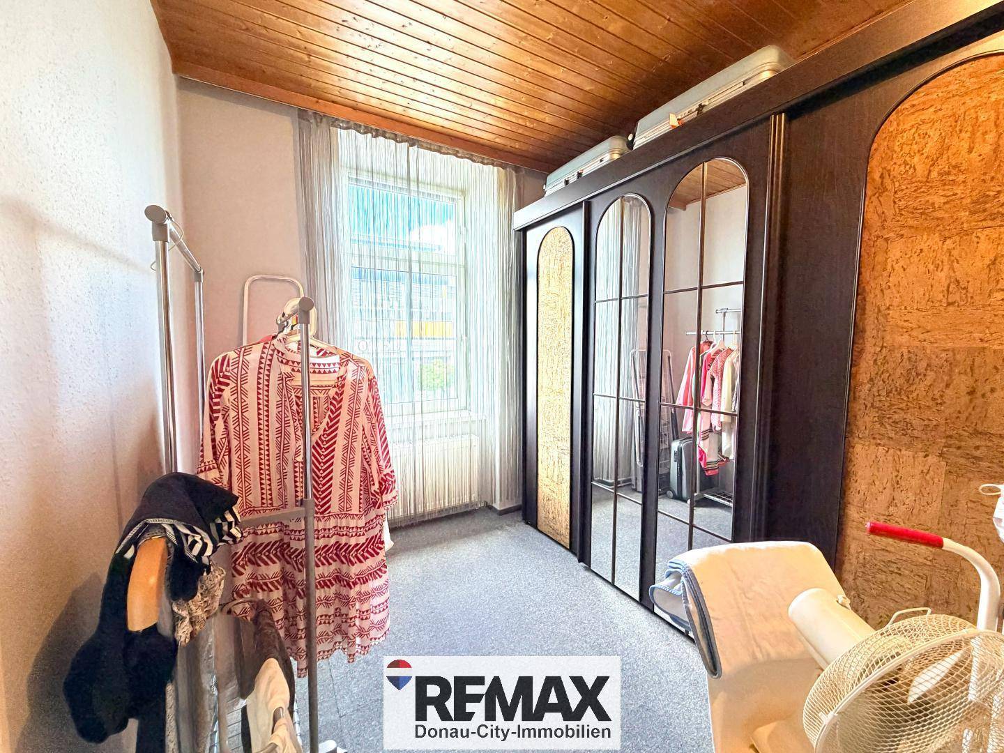 Schlafzimmer mit großem Kleiderschrank, Teppichboden und Fenster für natürliches Licht.
