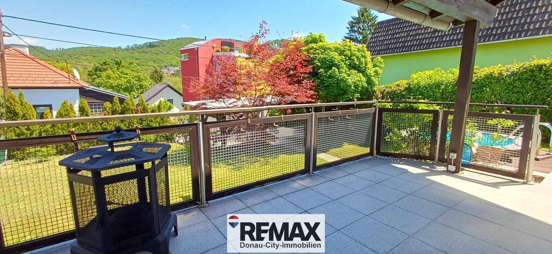 Geflieste Terrasse mit Metallgeländer und Blick auf die umliegende grüne Landschaft.