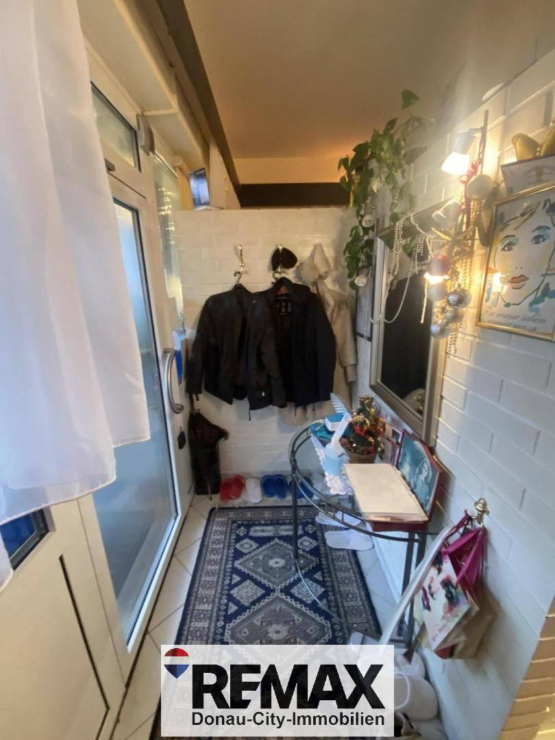 Schmaler Eingangsbereich mit weiß gestrichenen Ziegelwänden und Garderobe.