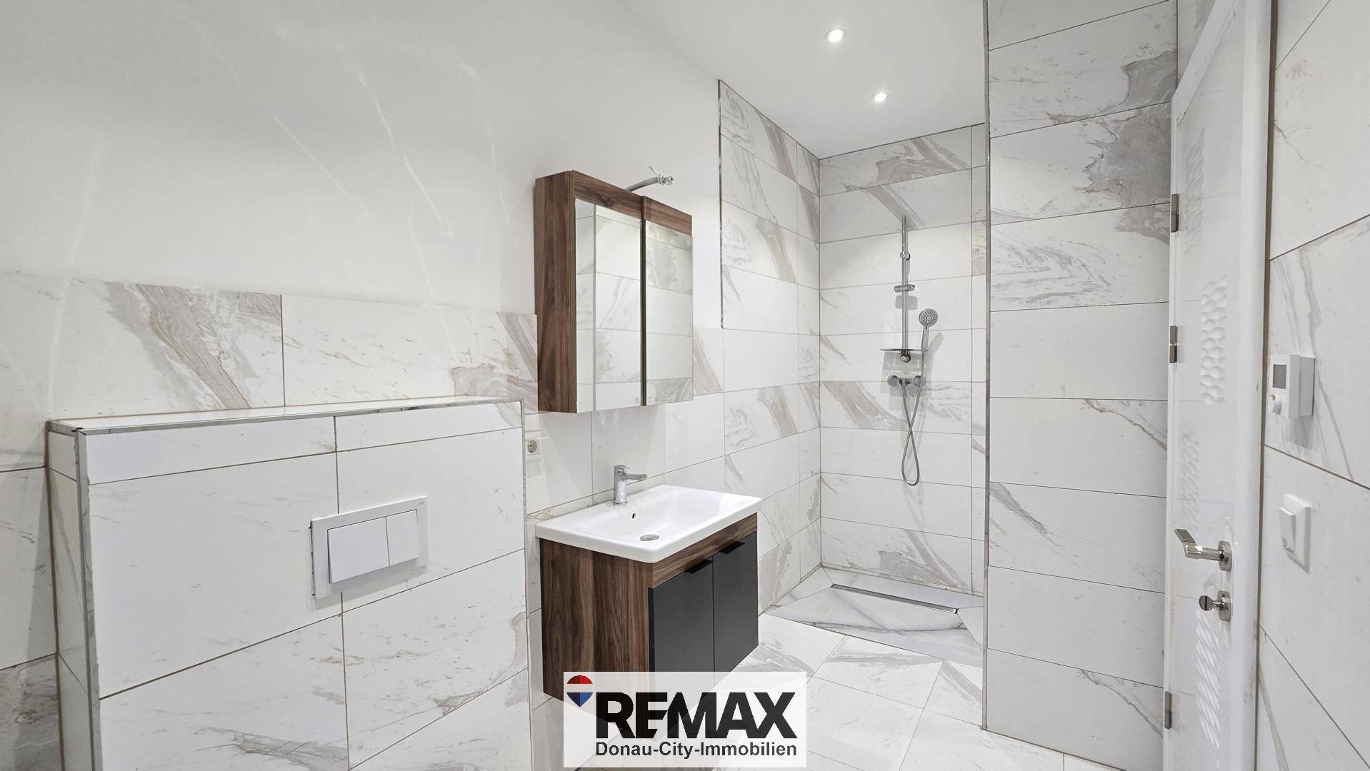 Modernes Badezimmer mit Marmorfliesen, begehbarer Dusche und elegantem Waschtisch mit Spiegelschrank.
