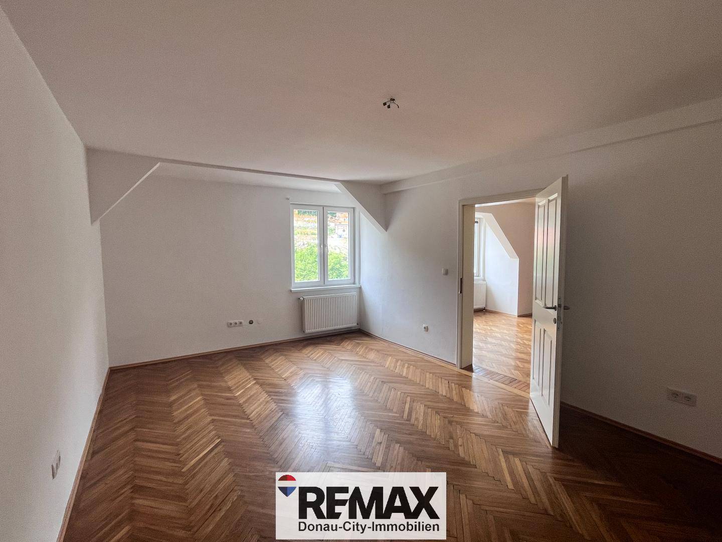 Helles Schlafzimmer mit Fischgrätparkett, Dachschräge und Blick ins Grüne.