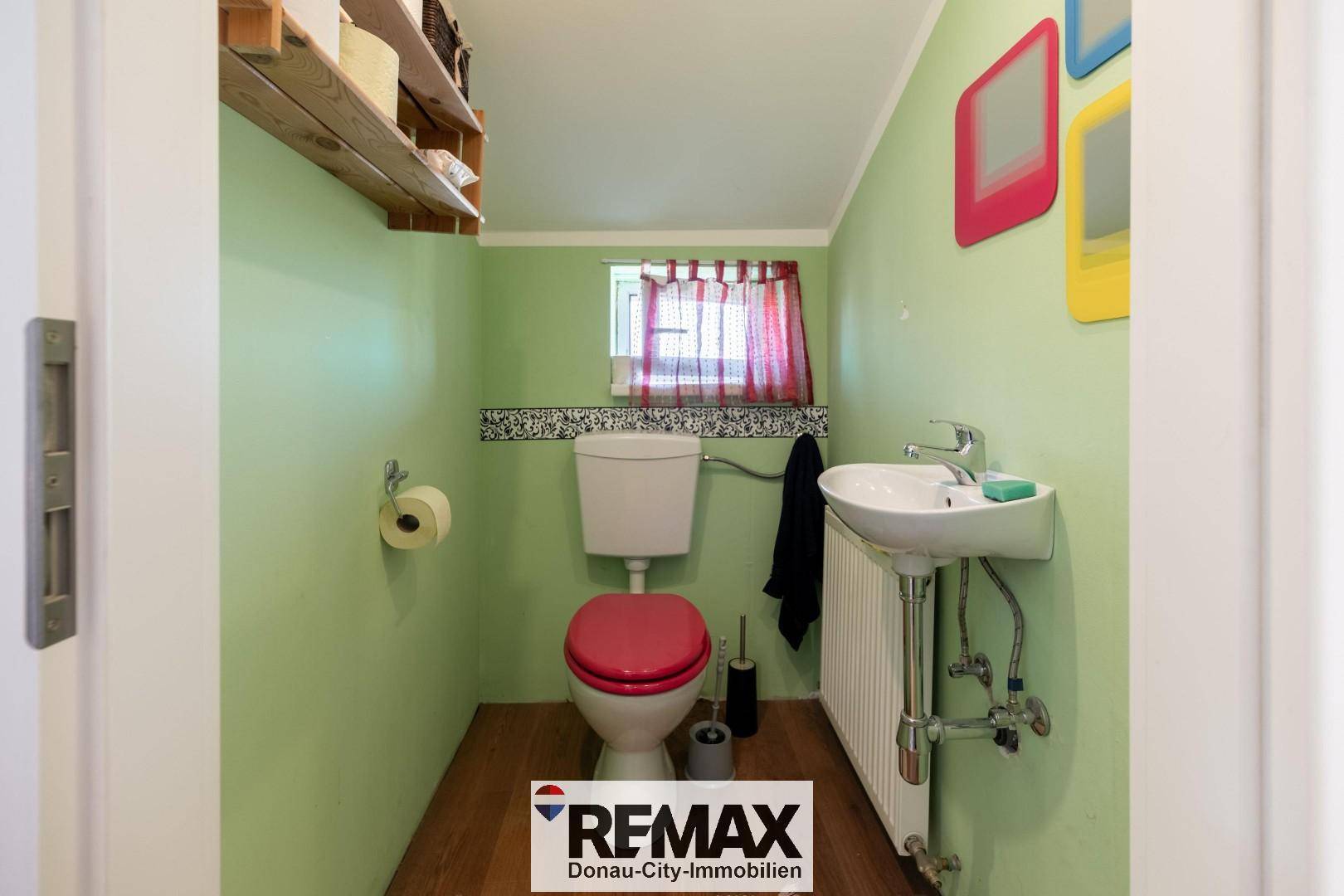 Kleines Gäste-WC mit grünen Wänden, Toilette und Waschbecken.