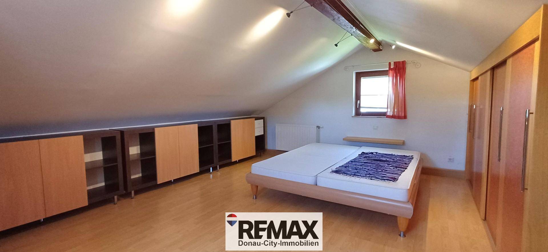 Schlafzimmer im Dachgeschoss mit Dachschräge, Holzboden und Einbauschränken.