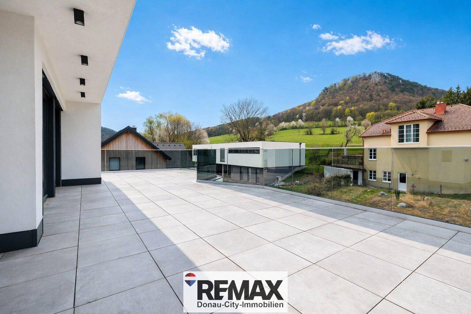 Weitläufige Terrasse mit modernen Fliesen und Blick auf die umliegende Landschaft und Berge.