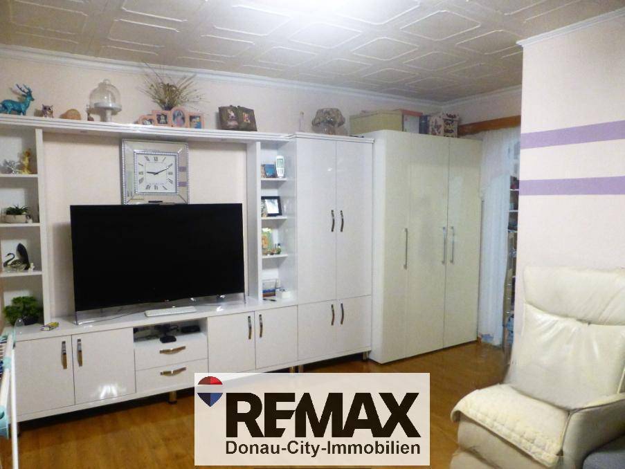 Wohnzimmer mit weißer Schrankwand, Fernseher und hellem Holzfußboden.