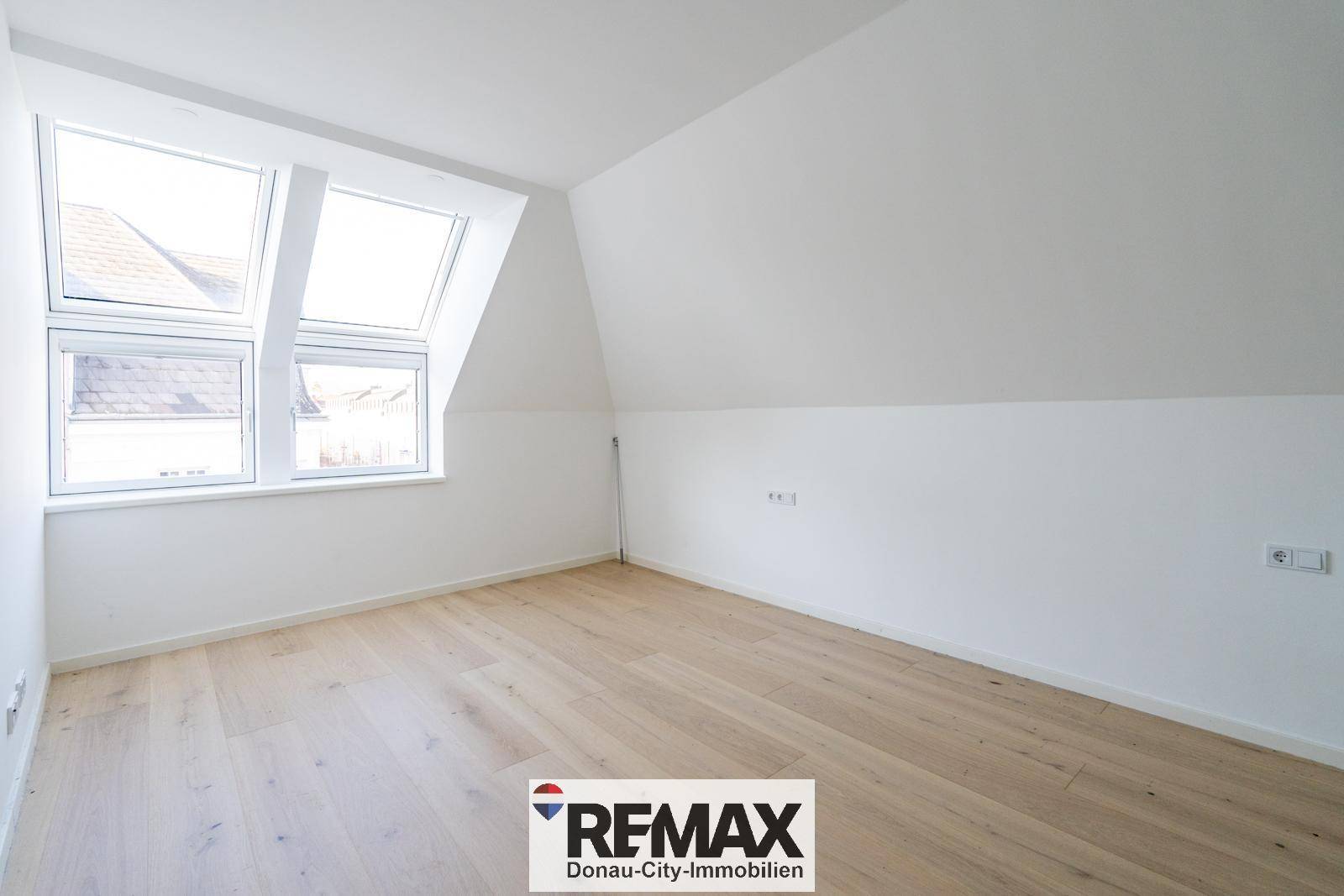 Helles Schlafzimmer mit Dachschrägen und großen Dachfenstern, ideal für ein Kinderzimmer.
