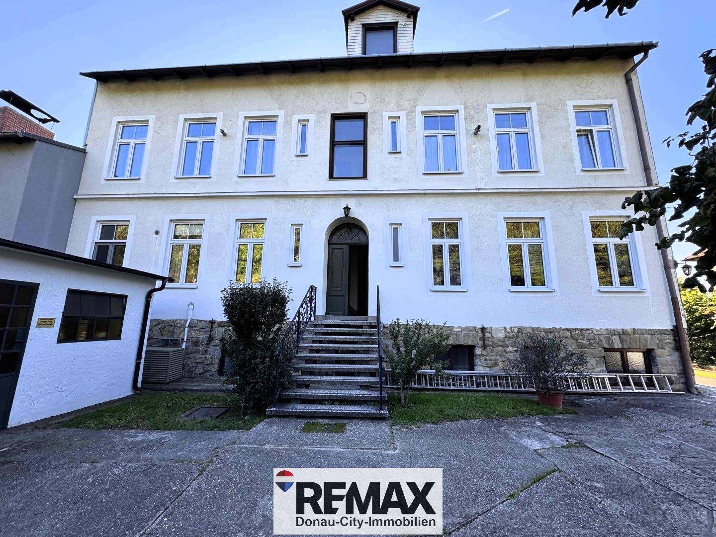 Repräsentativer Eingangsbereich eines historischen Gebäudes mit Steintreppe und klassischer Architektur.