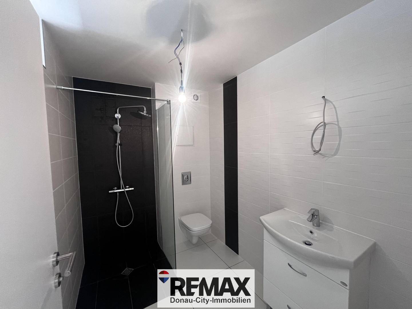 Modernes Badezimmer mit Dusche, WC und Waschtisch, ausgestattet mit weißen und schwarzen Fliesen.
