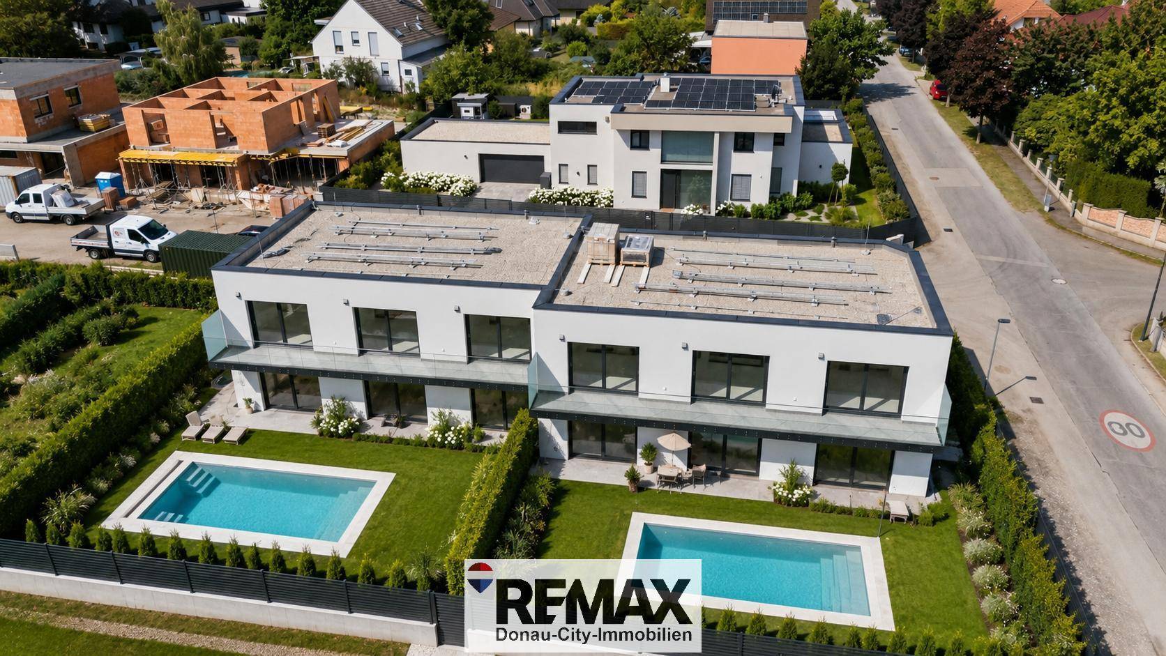 Luftaufnahme von zwei modernen Häusern mit Pools und Solaranlagen auf den Dächern.