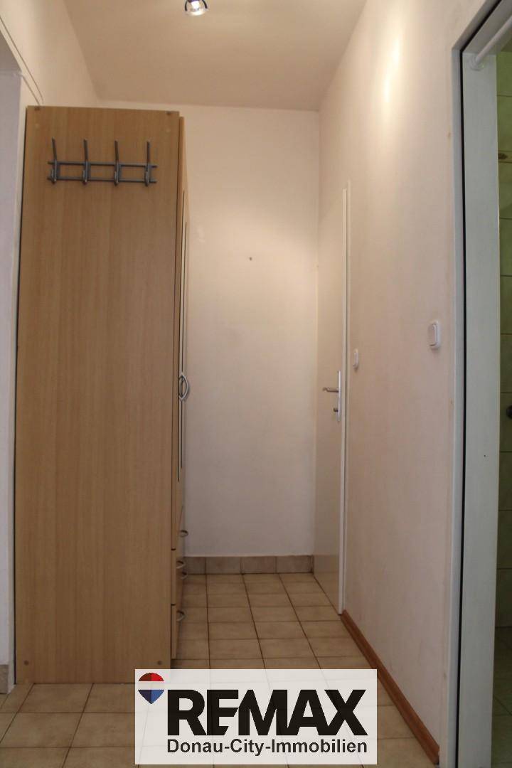 Flur mit Fliesenboden, Garderobenschrank und Zugang zu weiteren Räumen.