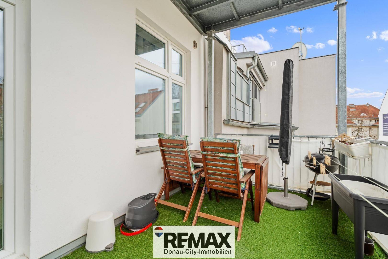 Balkon mit Kunstrasen und Gartenmöbeln, ideal für entspannte Stunden im Freien.