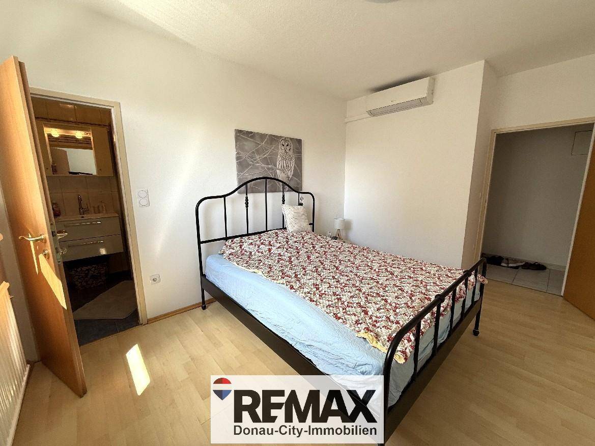 Schlafzimmer mit Doppelbett, Laminatboden und direktem Zugang zum Badezimmer.