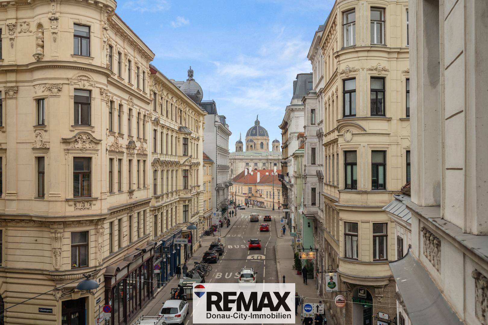 Panoramablick über eine historische Stadtstraße mit prächtigen Gebäuden und einer fernen Kuppel.