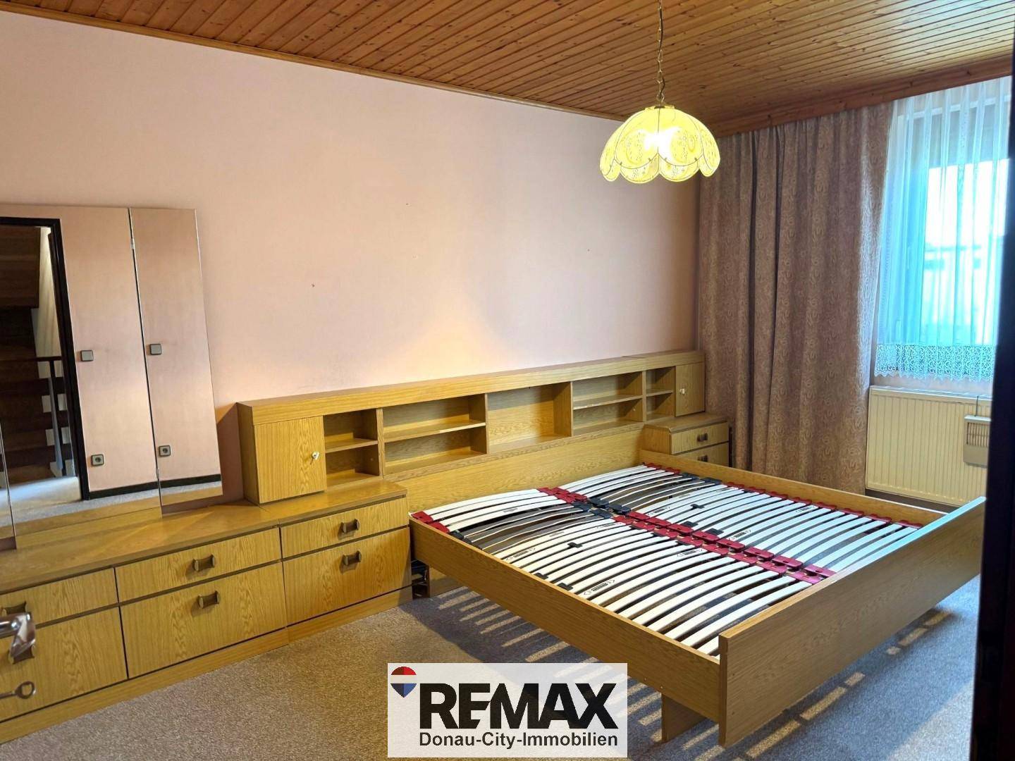 Schlafzimmer mit Doppelbett, Holzmöbeln und Teppichboden, bietet eine gemütliche Atmosphäre.