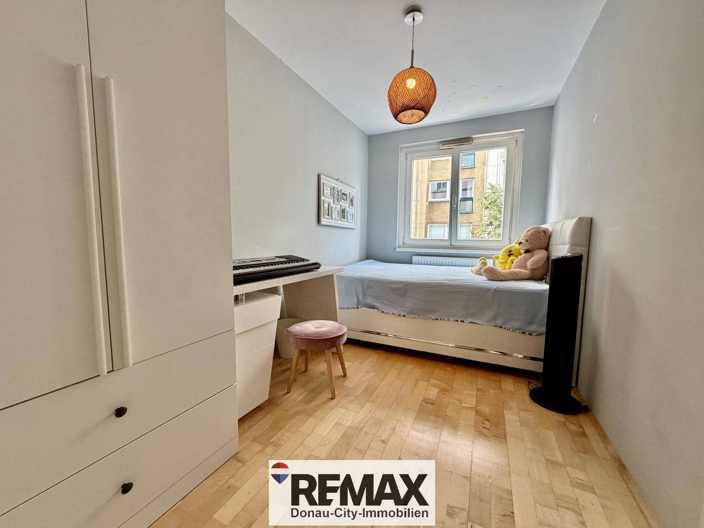 Gemütliches Kinderzimmer mit Einzelbett, Schreibtisch und Kleiderschrank, mit Holzboden und Fenster.