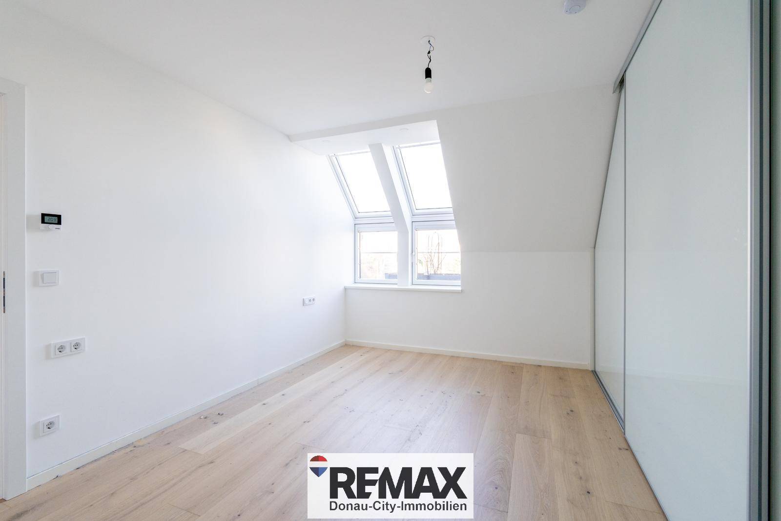 Helles Schlafzimmer mit Dachschrägen, Dachfenstern und integriertem Schiebetürenschrank.