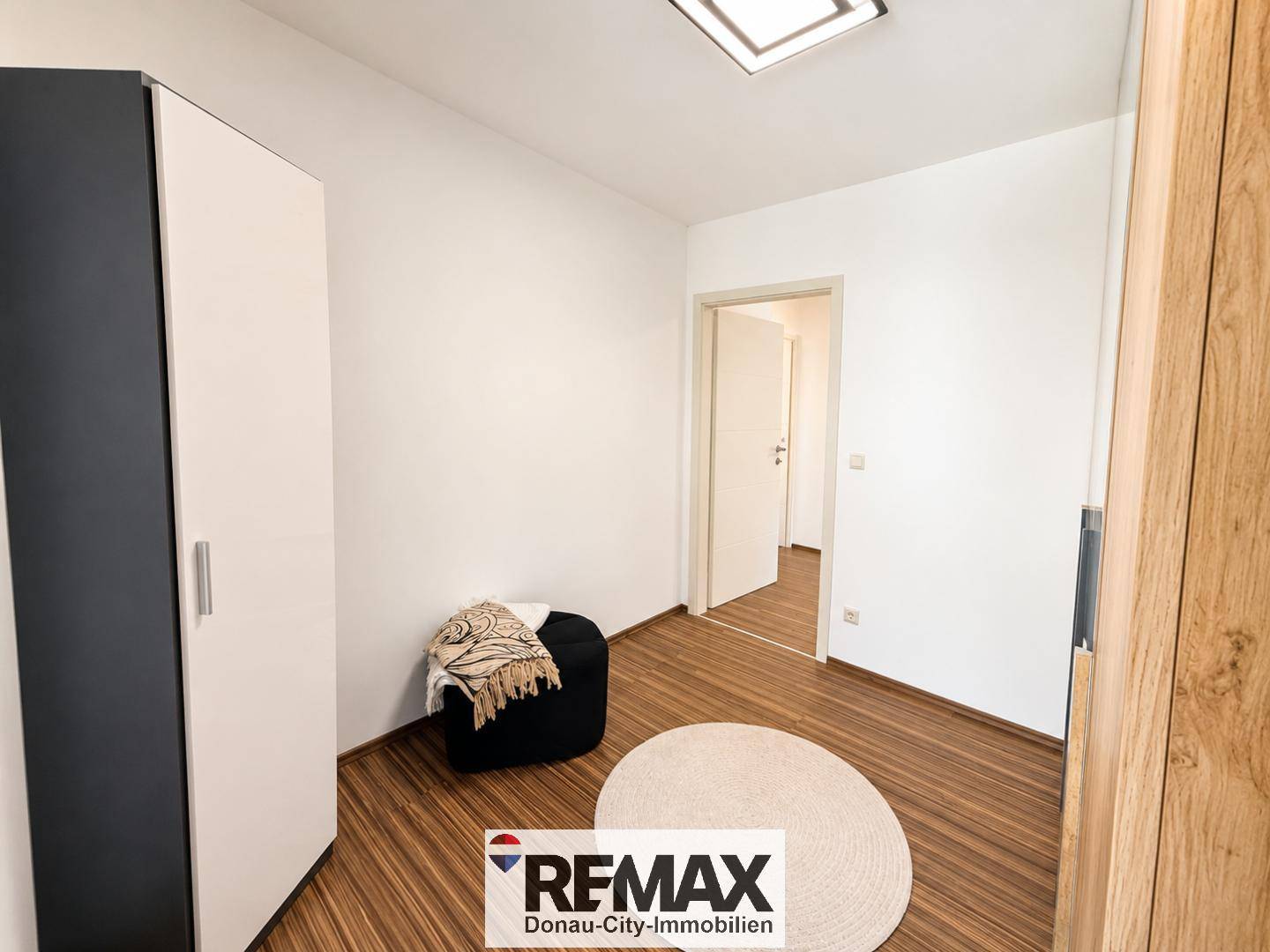 Helles Schlafzimmer mit Holzboden und weißem Kleiderschrank, bereit zur individuellen Gestaltung.