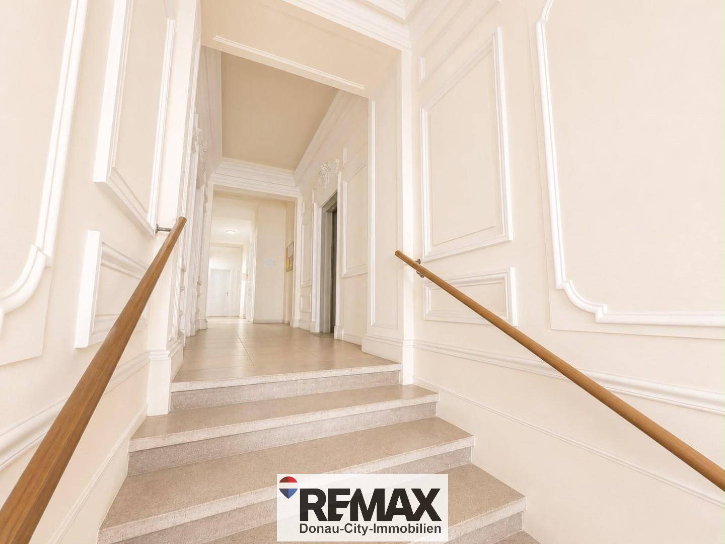 Eleganter Flur mit Stuckelementen an den Wänden und einer Treppe mit Holzgeländer.