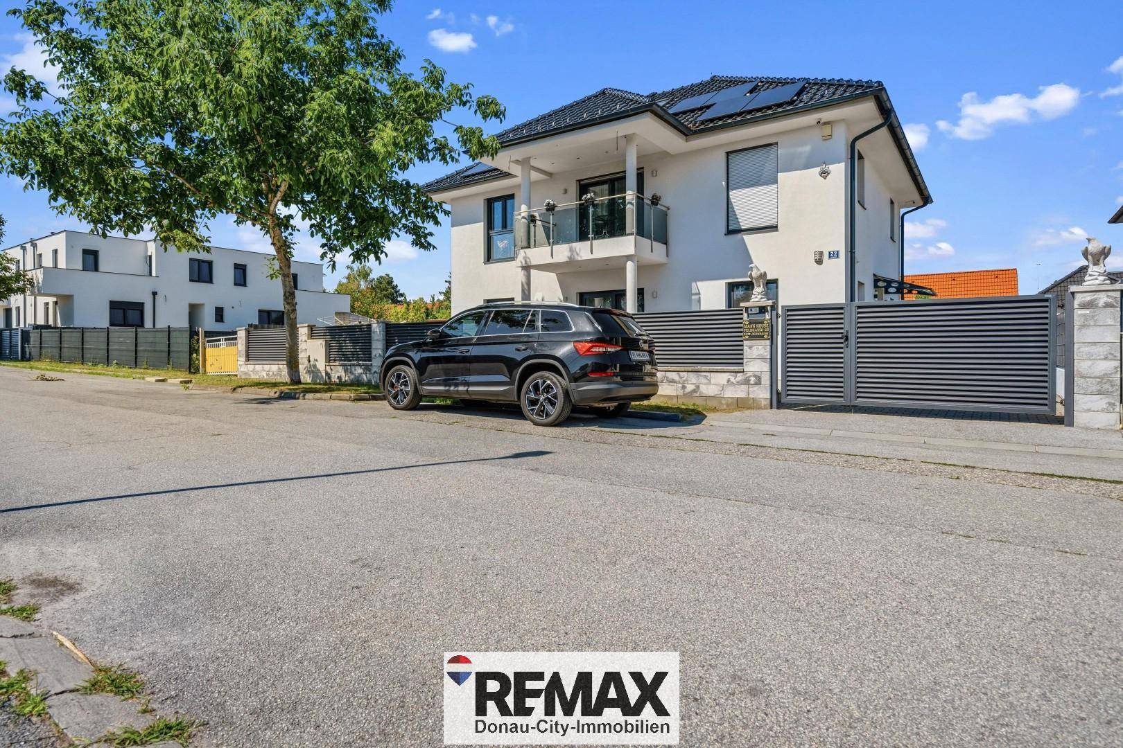 Ansicht des modernen Einfamilienhauses von der Straße mit gepflegtem Vorgarten und Einfahrt.