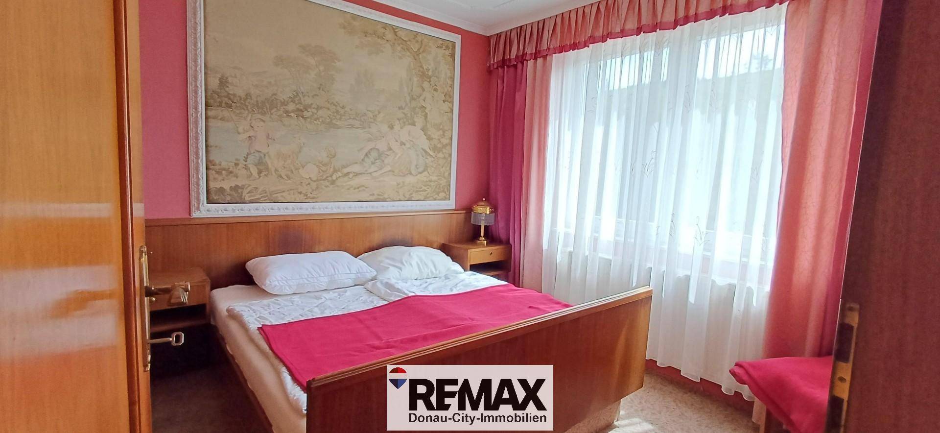Schlafzimmer mit Doppelbett, Holzmöbeln und rosa Vorhängen, bietet eine gemütliche Atmosphäre.