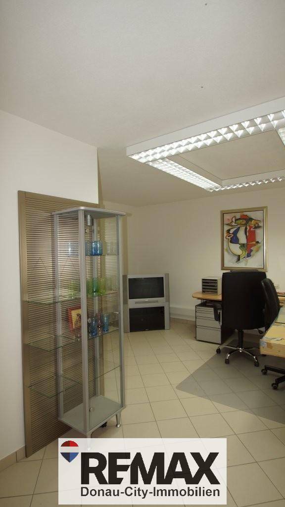 Büro mit Vitrine, Schreibtisch und Bürostuhl, bietet eine funktionale Arbeitsumgebung.