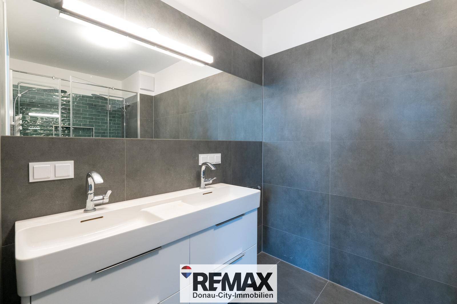 Elegantes Badezimmer mit Doppelwaschbecken, großem Spiegel und modernen Armaturen.