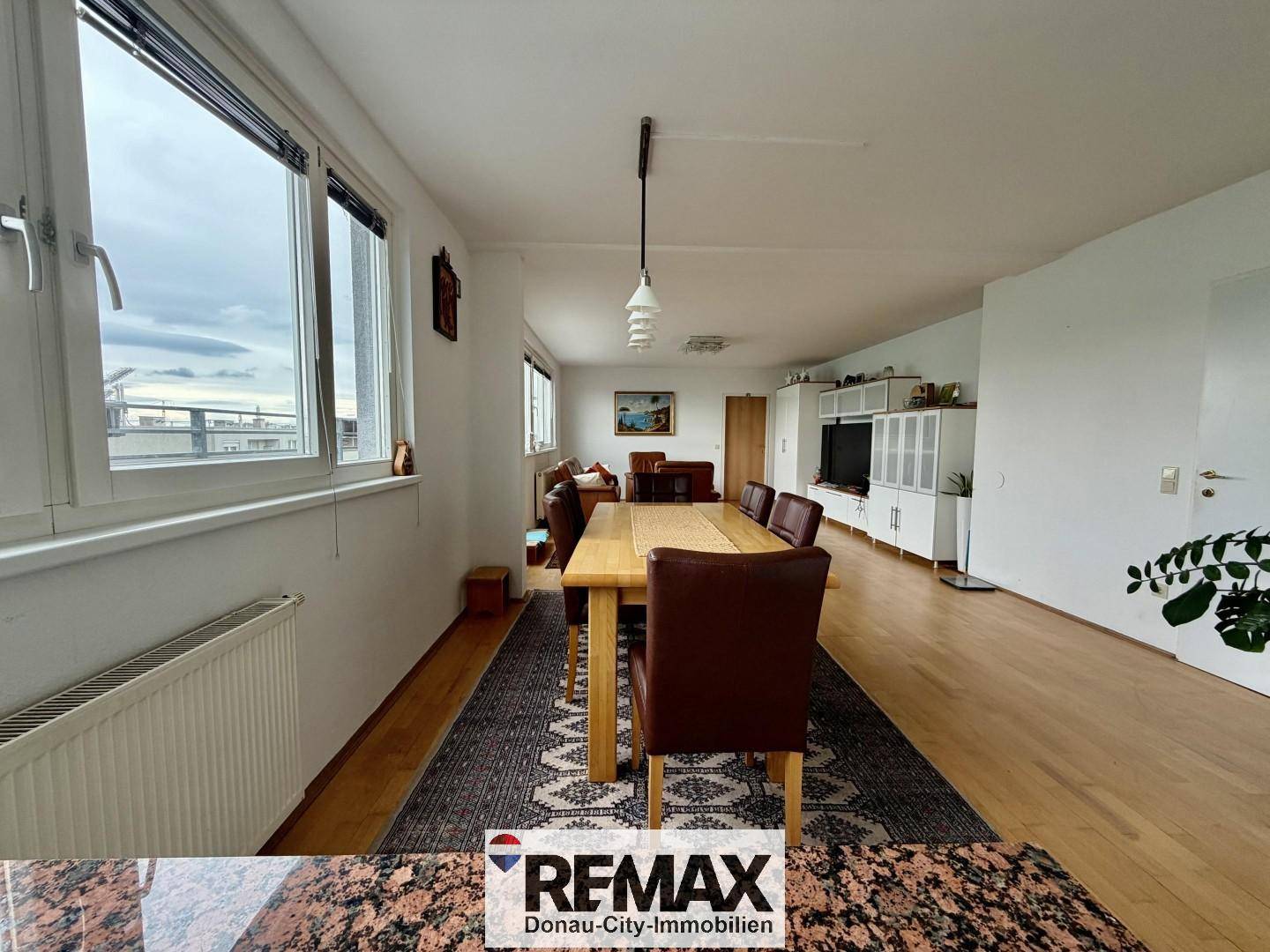 Essbereich mit Holztisch und Blick auf die Stadt, verbunden mit dem Wohnzimmer.