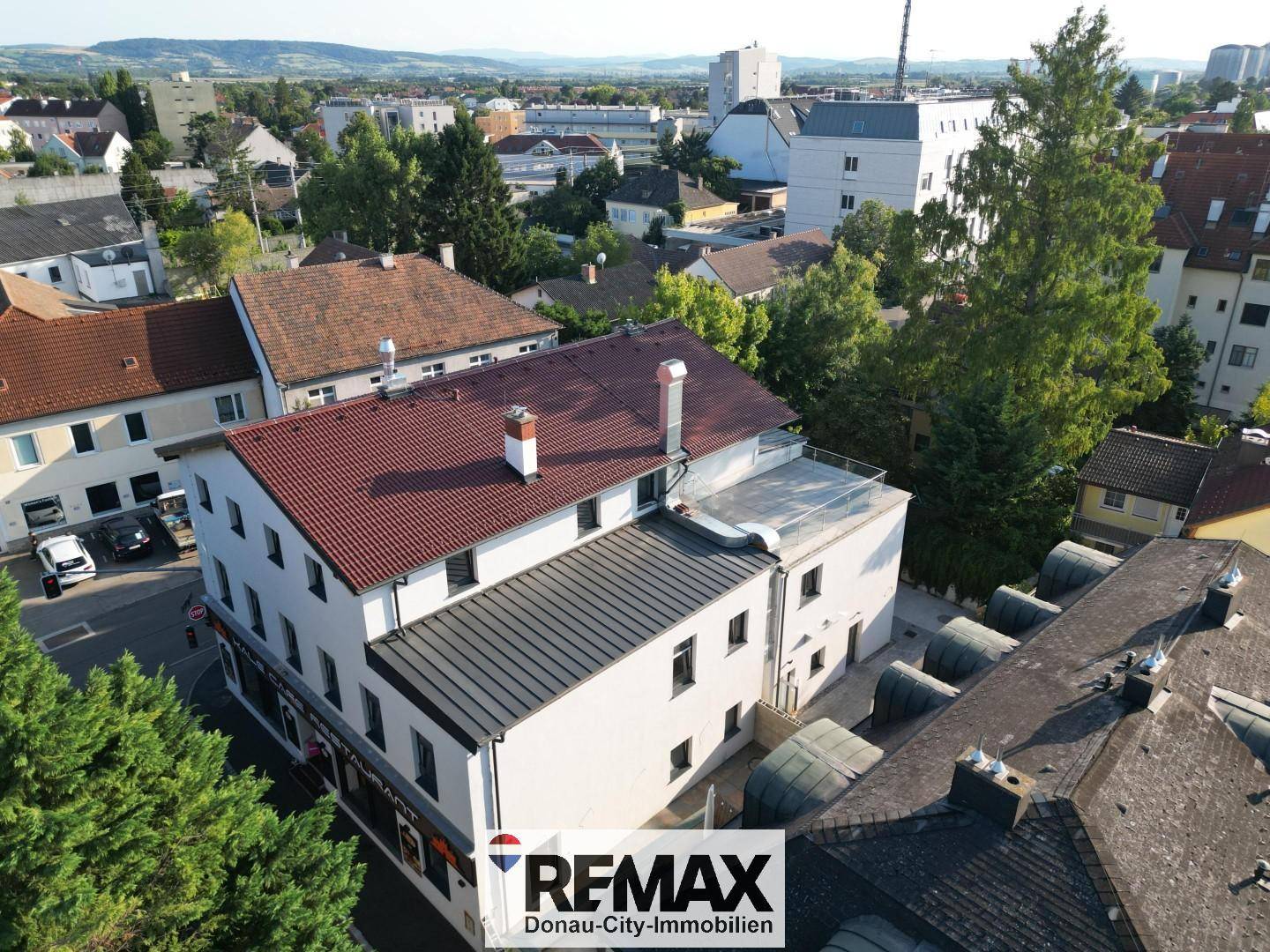 Luftaufnahme eines Gebäudekomplexes in städtischer Umgebung mit umliegenden Häusern und Grünflächen.