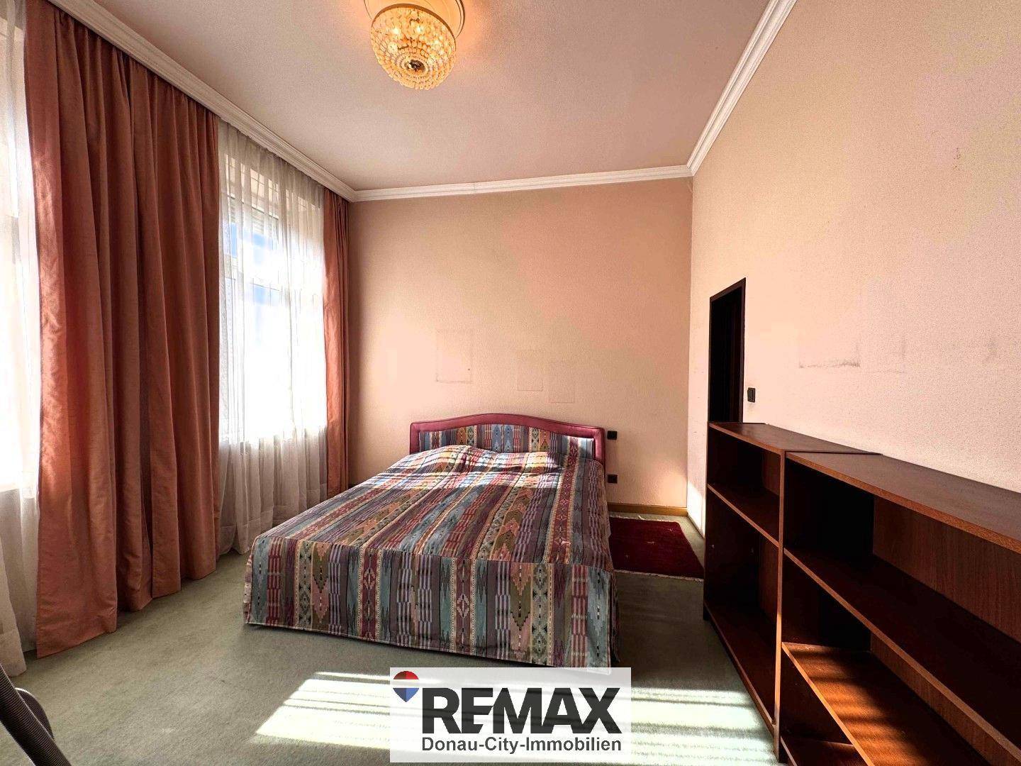 Schlafzimmer mit Teppichboden, Doppelbett und großem Fenster, bietet viel natürliches Licht und Raum.