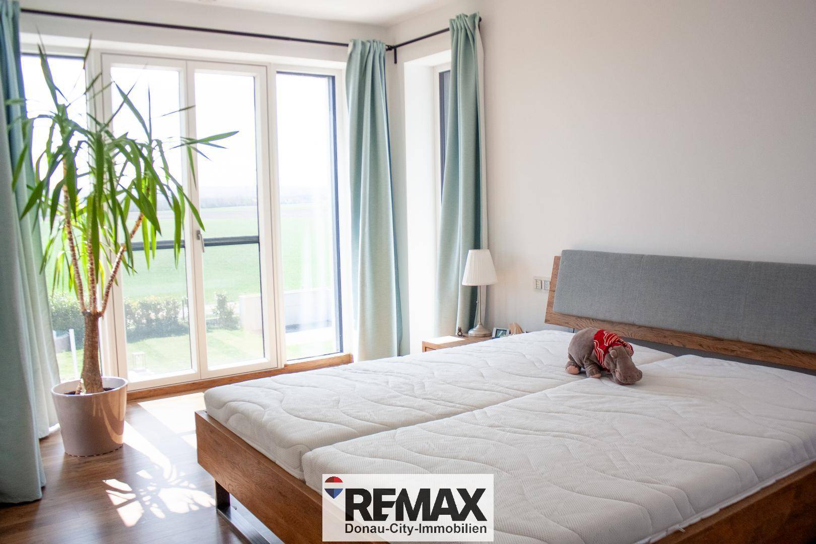 Helles Schlafzimmer mit Doppelbett, Holzboden und Zugang zu großen Fenstern mit Weitblick.
