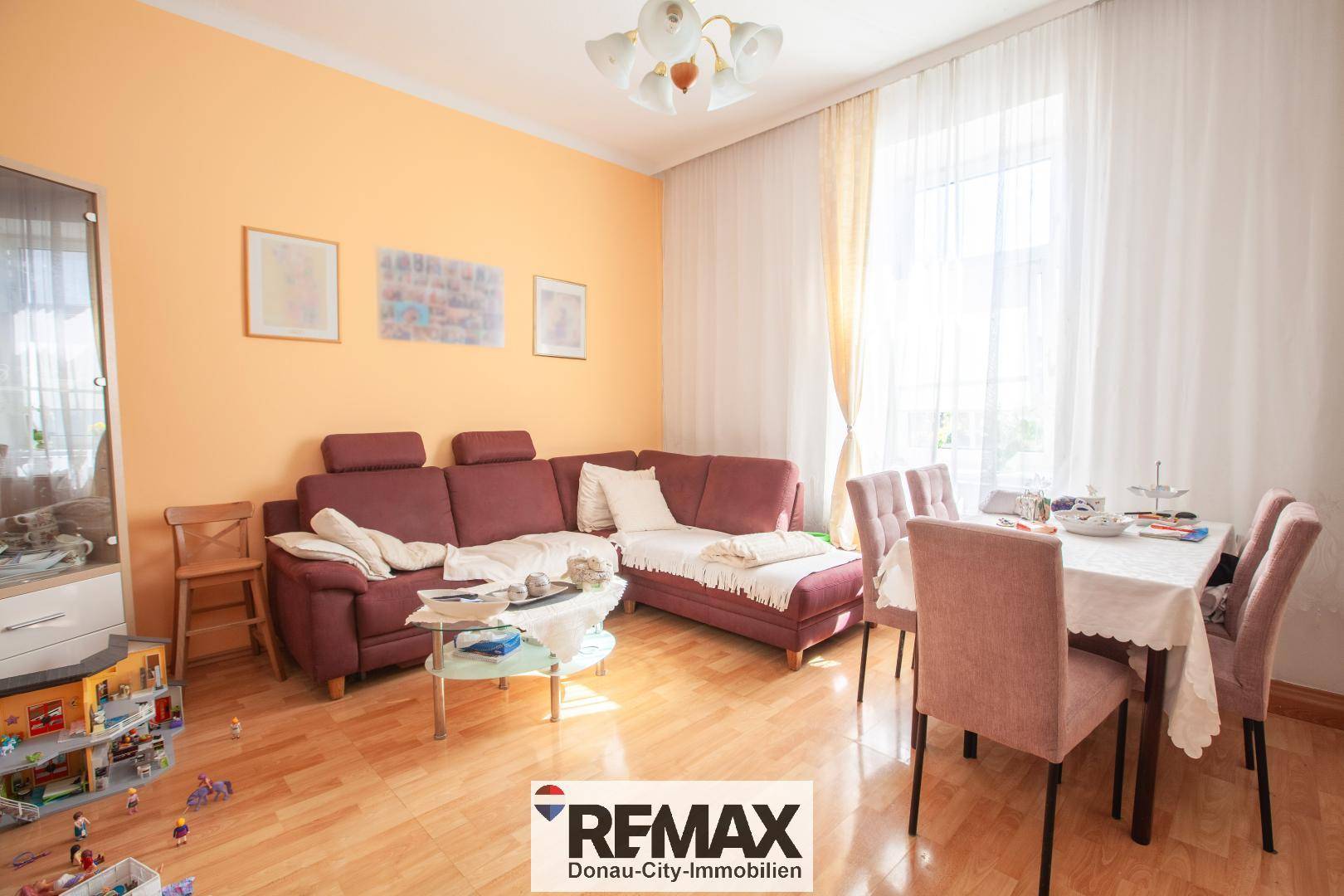Gemütlicher Wohn-Essbereich mit L-förmigem Sofa, Esstisch und hellem Holzfußboden.
