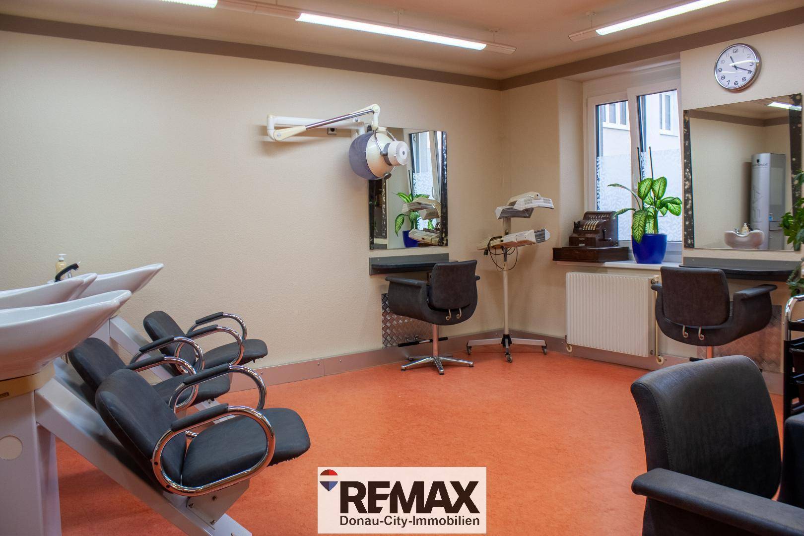 Waschbereich in einem Friseursalon mit mehreren Waschbecken, Styling-Stühlen und einem Haartrocknerarm.