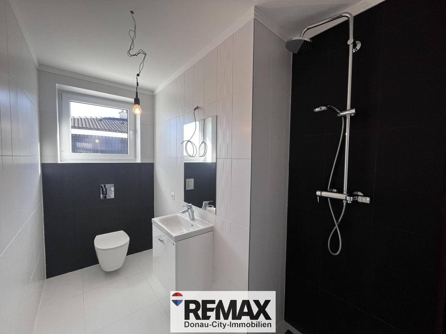Modernes Badezimmer mit Dusche, Waschbecken und Fenster, in Schwarz-Weiß-Design.