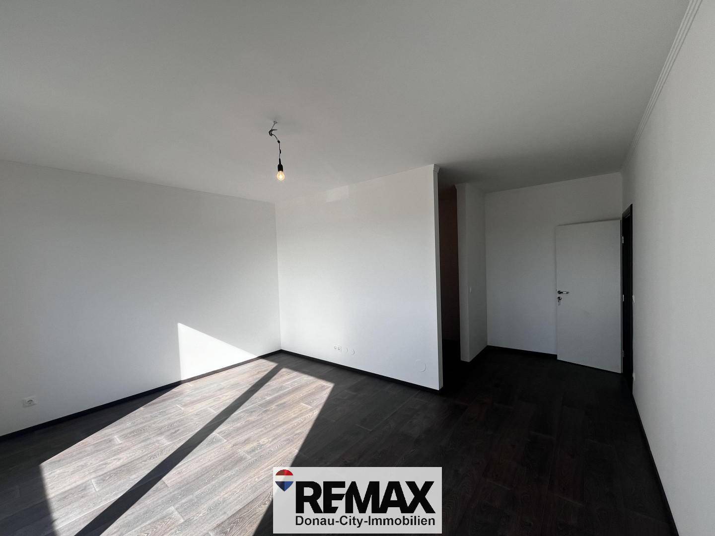 Helles Zimmer mit dunklem Holzboden und weiß gestrichenen Wänden, vielseitig nutzbar.