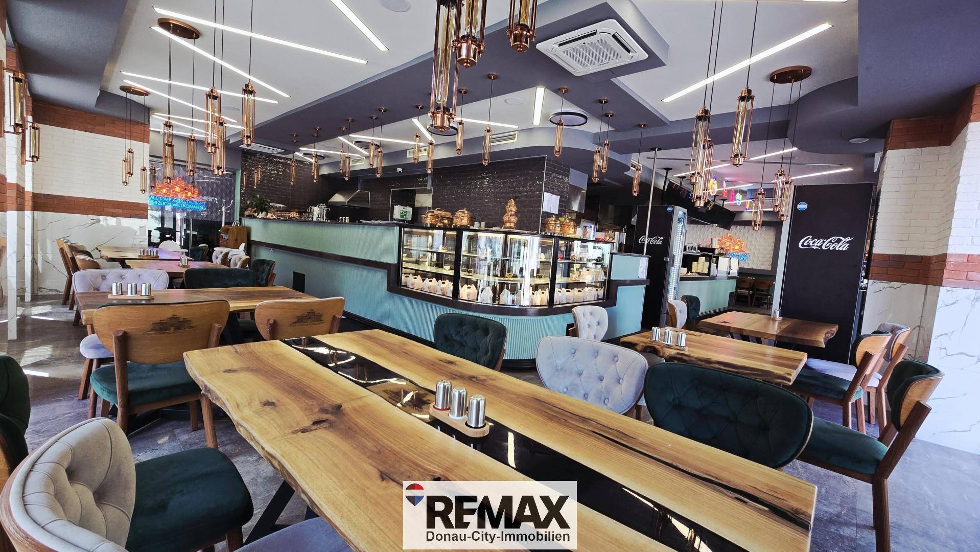 Einladender Restaurantbereich mit modernen Holztischen, bequemen Stühlen und stilvoller Beleuchtung.
