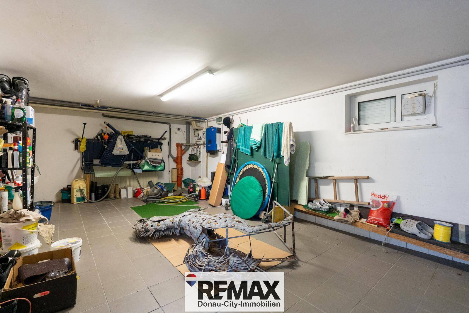 Funktionaler Garagenraum mit kleinem Fenster, genutzt zur Aufbewahrung von Werkzeugen und Haushaltsgegenständen.