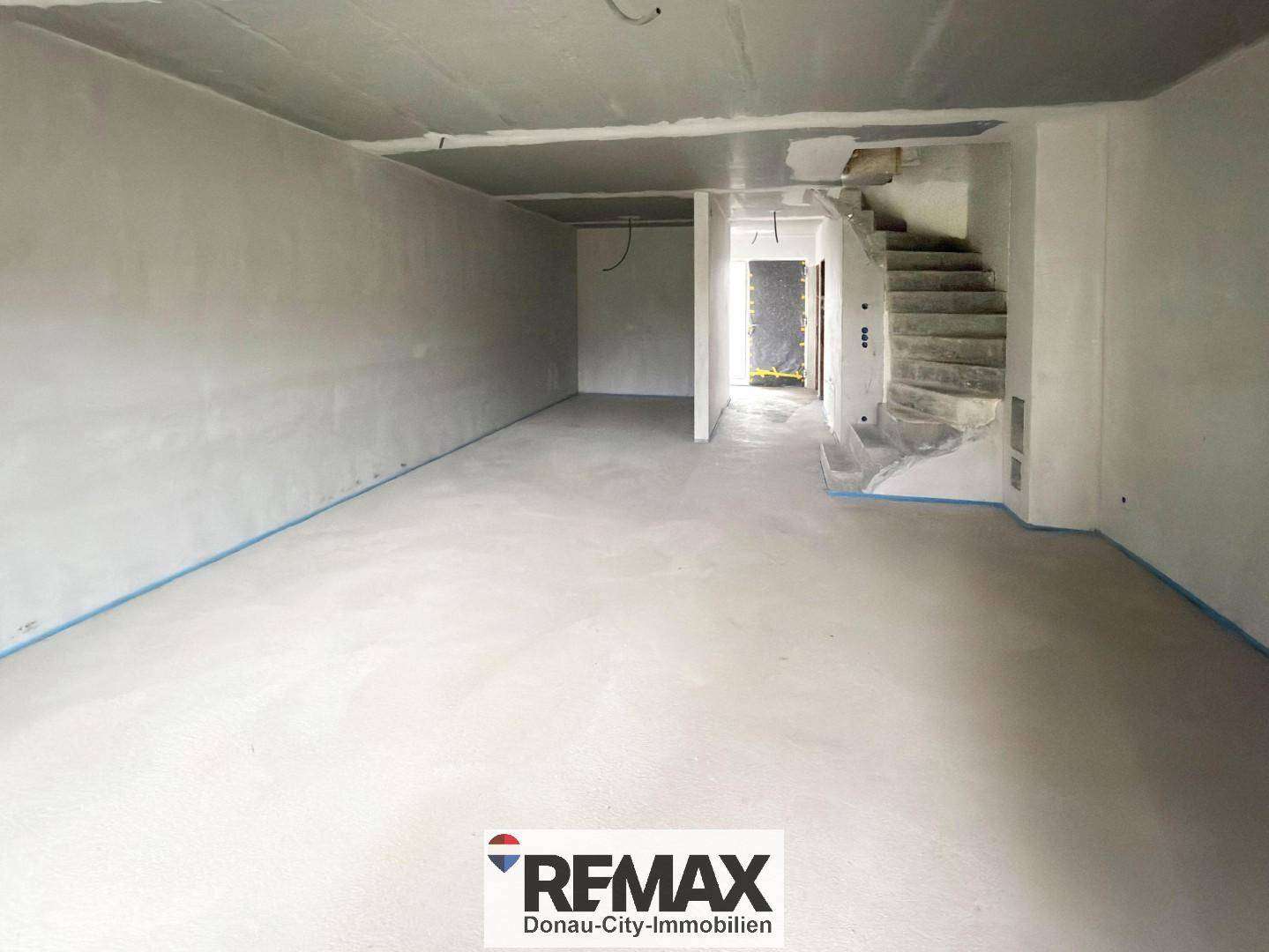 Unfertiger Innenraum mit Betonboden und Treppenaufgang, bereit für den weiteren Ausbau.