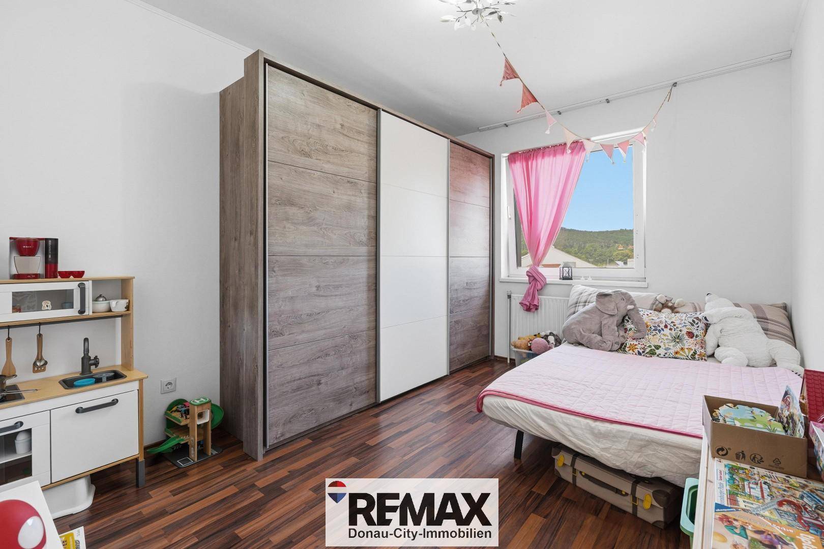 Kinderzimmer mit großem Kleiderschrank, Bett und Spielzeug.