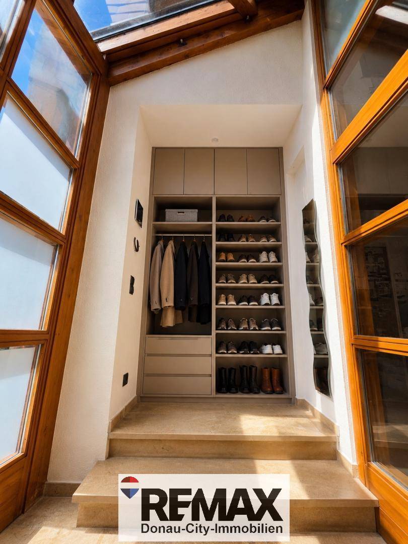 Praktischer begehbarer Kleiderschrank mit viel Stauraum für Kleidung und Schuhe, integriert in einen Übergangsbereich.
