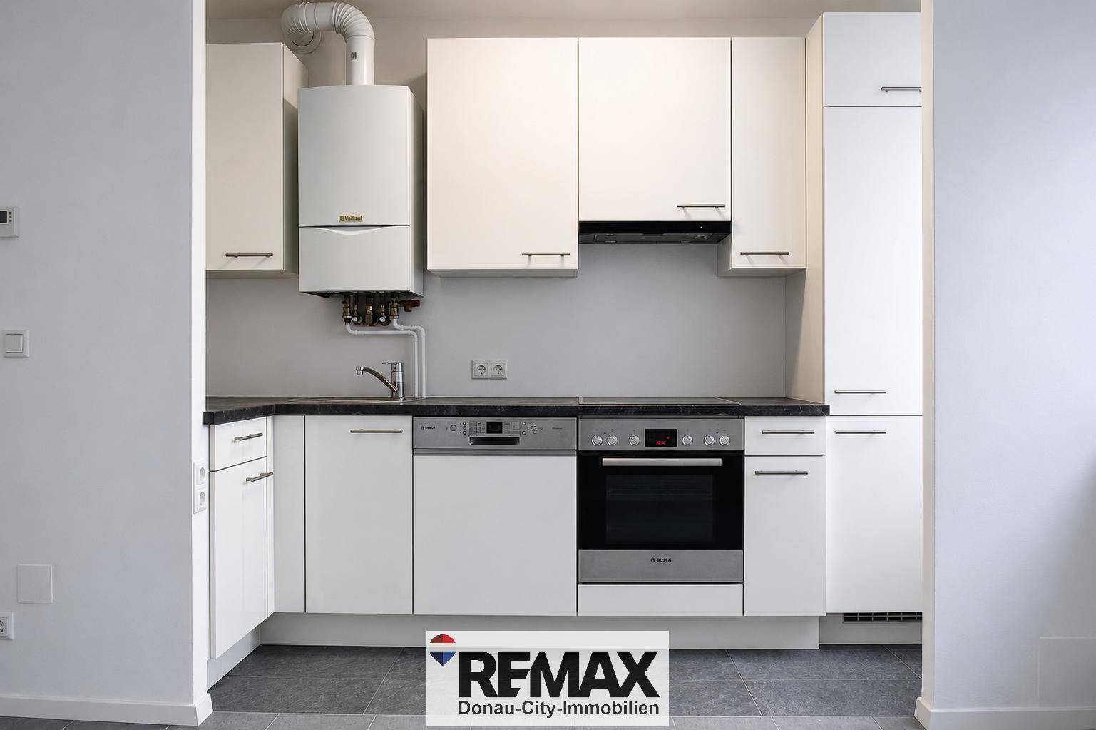 Leere Küche mit weißen Schränken, Spüle, Geschirrspüler und Backofen, ideal für neue Mieter.